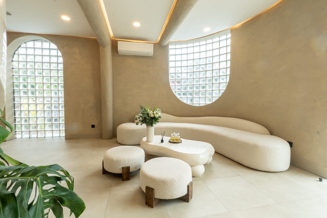 The GLAZE lounge — curved bouclé sofa beneath glass-block light