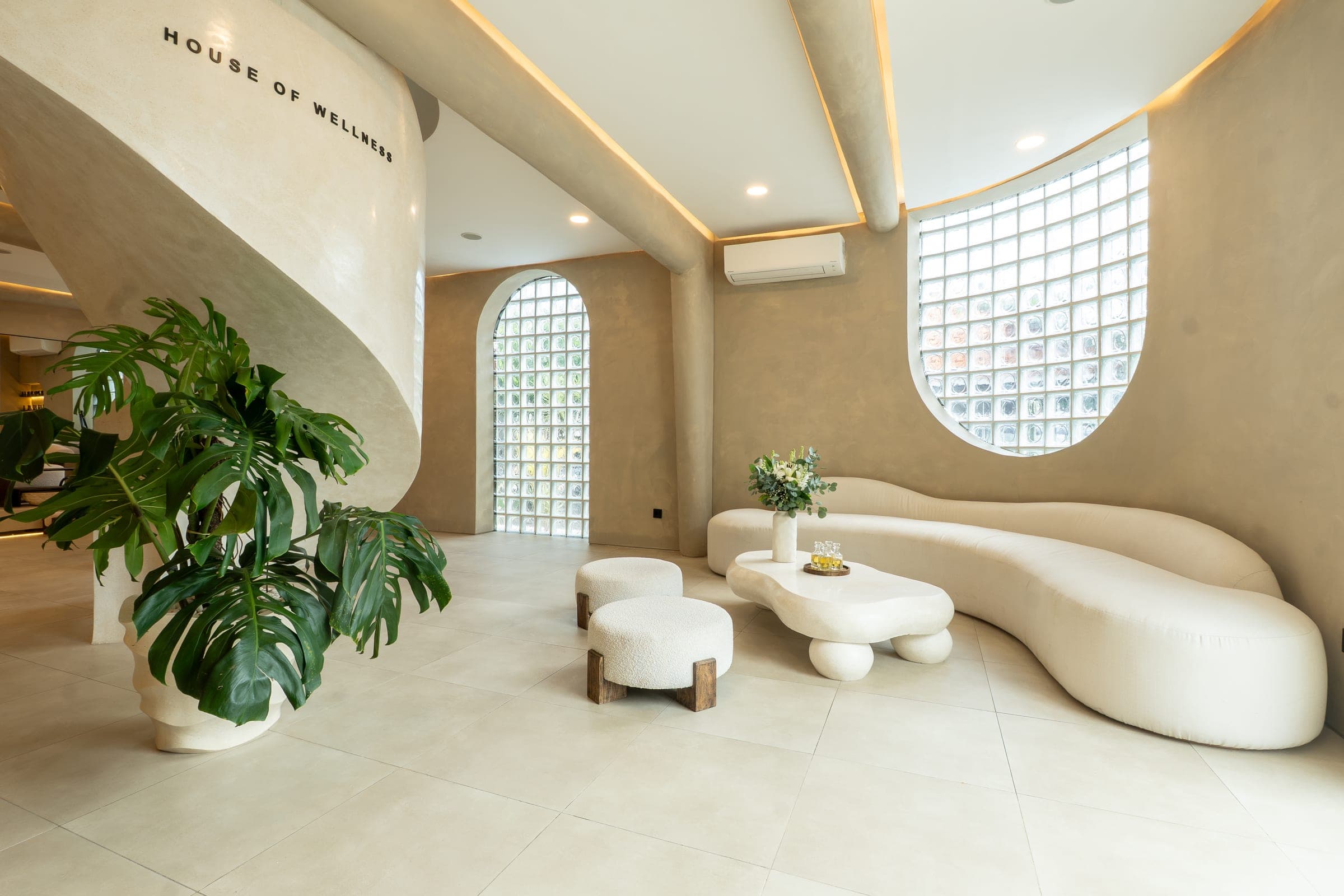The GLAZE reception lobby — curved sofas, glass-block walls and a monstera